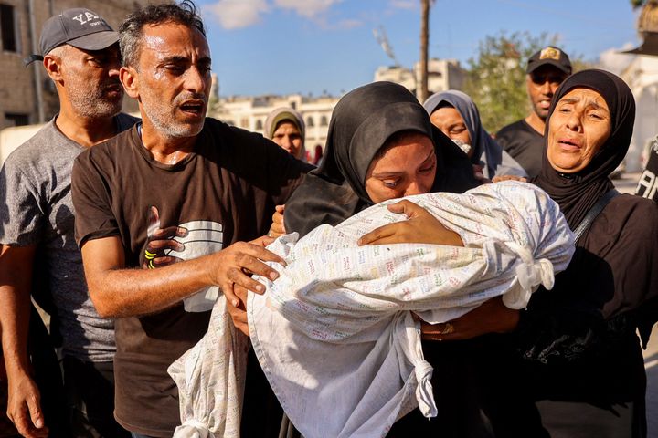 A woman cries as she holds the shrouded body of her child who was killed during an Israeli strike on a school house for displaced Palestinians in the Gaza City countryside of Zaytoun on September 21, 2024.